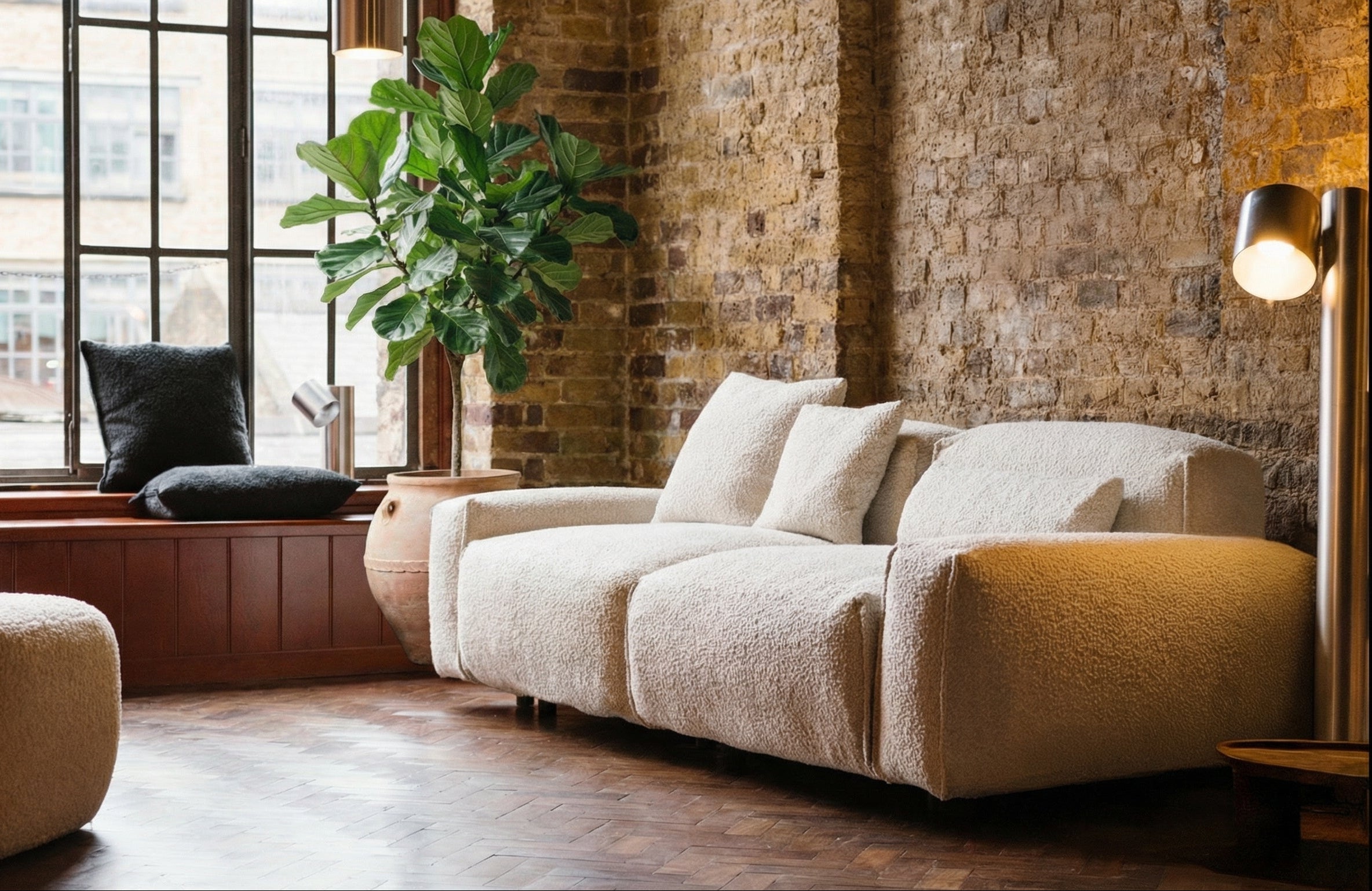 Modern living room with a beige sofa, ottoman, and large windows.